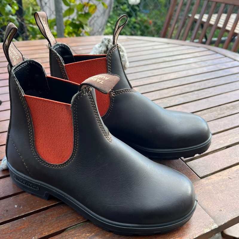 Brown Blundstone Chelsea boots with orange inner lining on a wooden table outdoors. Originals Series 1918