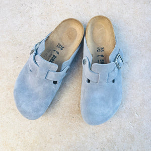 Pair of light blue suede Birkenstock clogs on a light background