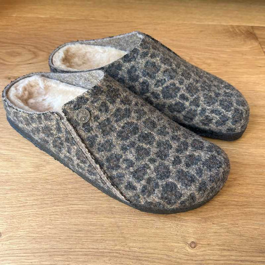 Pair of Birkenstock leopard print slippers on a wooden floor