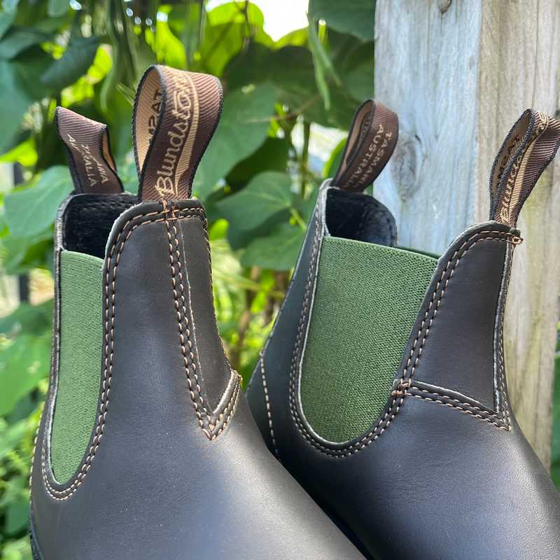 Pair of Brown leather and olive green insert Blundstone boots against an outdoor background.