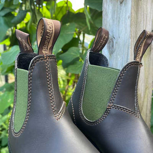 Pair of Brown leather and olive green insert Blundstone boots against an outdoor background.