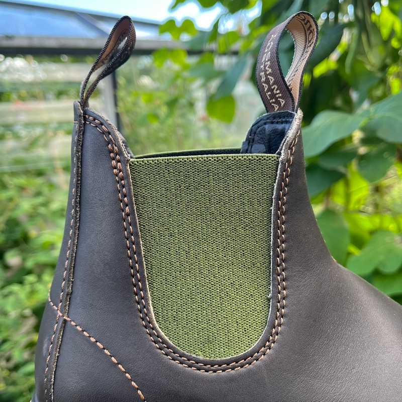 Close-up of a brown leather blundstone boots with olive green lining, outdoors.